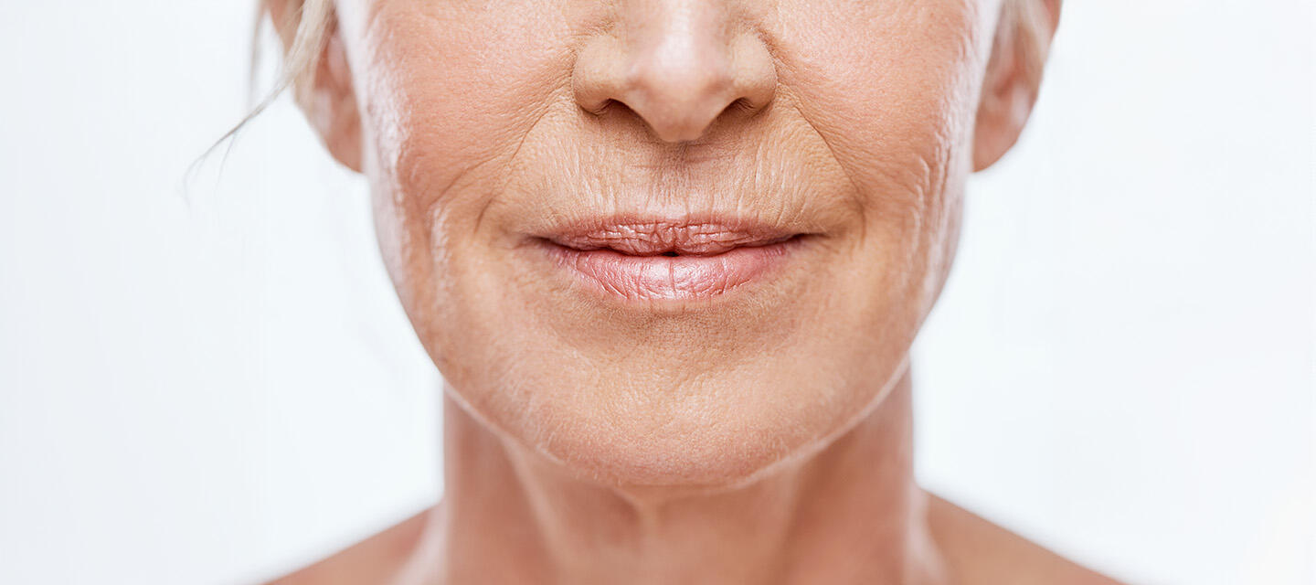 Closeup of an elderly woman with wrinkles, light pink lip gloss on her lips